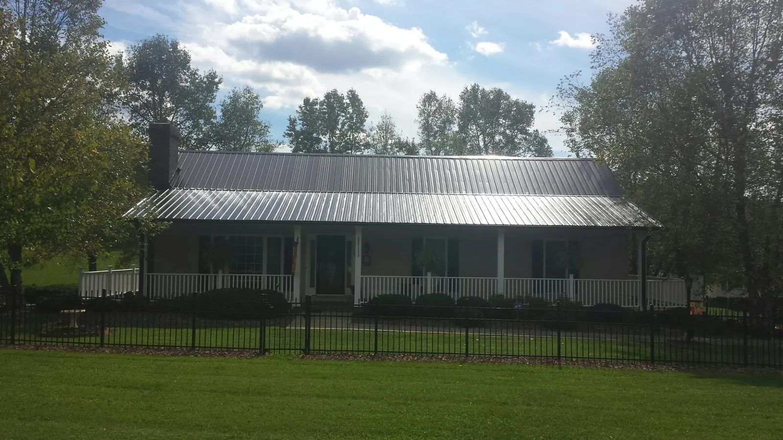 Gray metal roof on a brick ranch with a full width front porch — Gutter Guard Installation work by our crew in Carlton