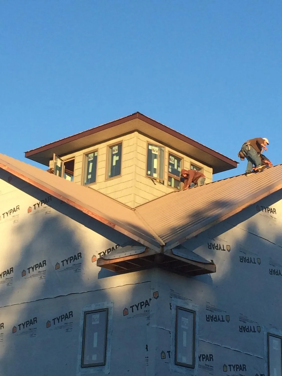 Roofers working around a rooftop cupola on a new metal roof at sunset — Roof Waterproofing in Carlton by Roofing Brothers